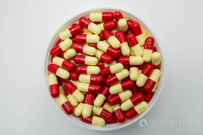 红色淡黄色胶囊丸塑料容器在白色背景上的顶视图