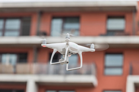 白色的无人驾驶飞机，直升机，飞行在城市的照片相机。体育概念无人机