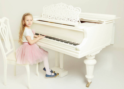 男孩可爱又可爱, 把手指放在钢琴键盘上.孩子们在乐器旁度过闲暇时光.