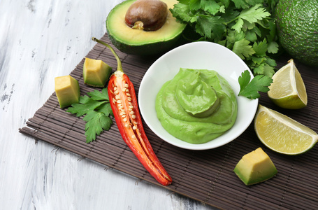 在木制的桌子上的碗里新鲜的鳄梨酱照片