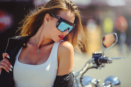 随便的美丽女人坐在大旅游摩托车在街头的灿烂的笑容在阳光明媚的一天