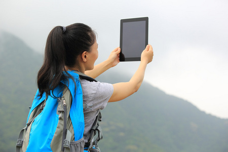 徒步旅行者在山顶 tablet pc 上