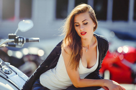 随便的美丽女人坐在大旅游摩托车在街头的灿烂的笑容在阳光明媚的一天