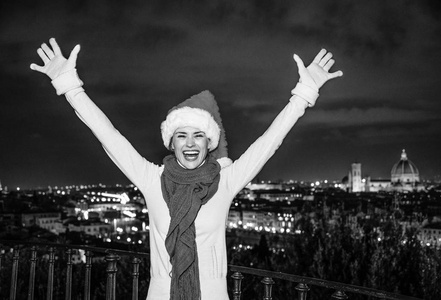旅行充满灵感在圣诞节的时候在佛罗伦萨。微笑的年轻女子，在意大利佛罗伦萨的喜悦在米开朗基罗广场圣诞帽子