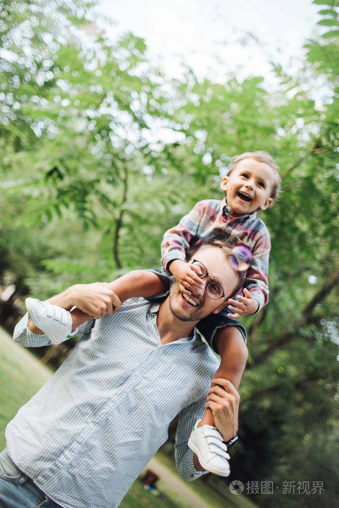 儿子坐在父亲肩膀上公园户外