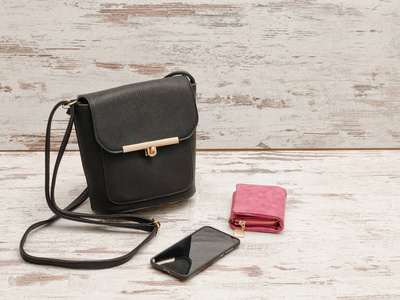 小黑人女性手提包 钱包和手机上的一个木制的背景。时尚概念