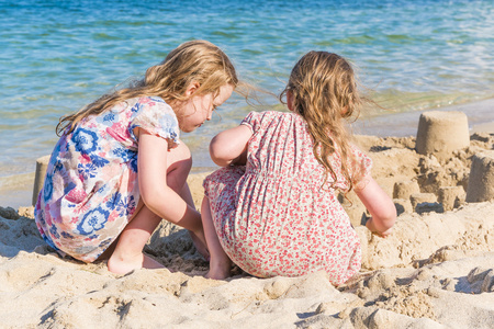 两个小女孩在海边玩沙子