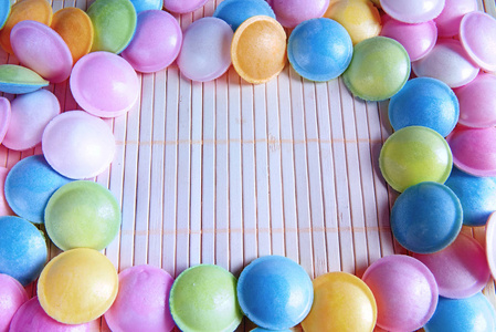 混合的多彩糖果白色木背景上。七彩的棒棒糖和不同彩色圆糖果。顶视图