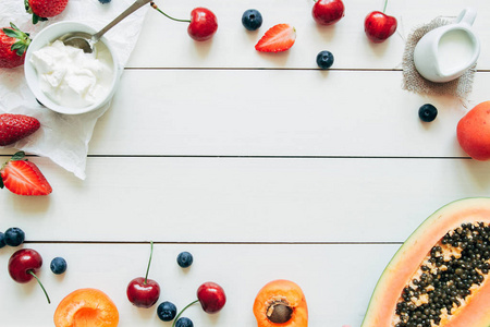 夏天的水果。新鲜多汁的浆果和木瓜上白色的木桌，顶视图