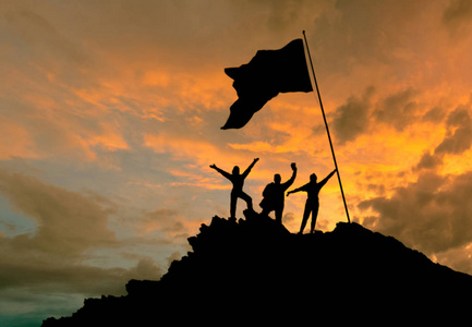 征服了高度,轮廓的三人,一座山上,用一面旗照片