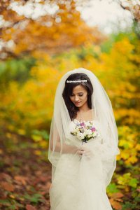 美丽的黑发新娘在秋天公园散步