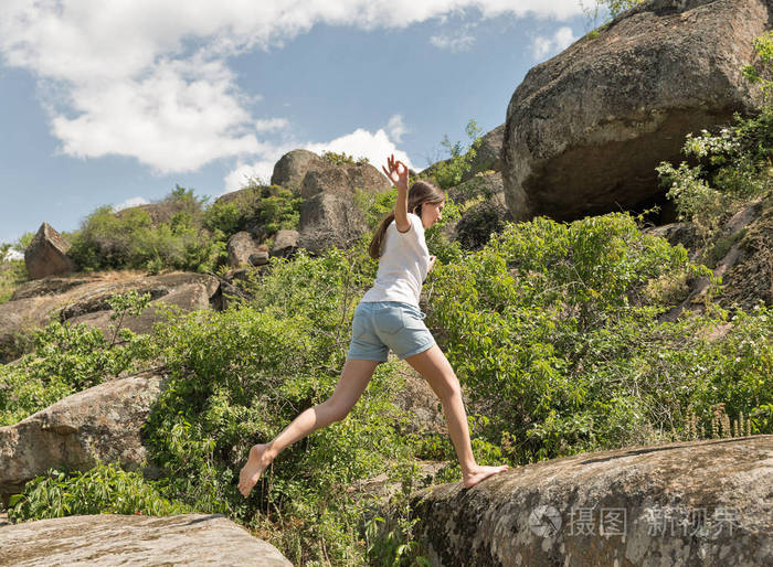 年轻的健身女人赤脚跑在山岩石