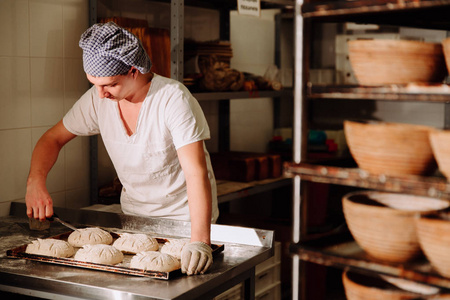 贝克对面包的面团进行手动的切口。Bread.Bakery 的研制