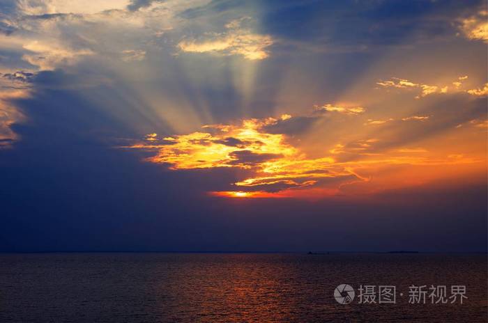 太阳光线通过湖面多云黑暗的天空