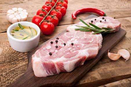生肉。猪排配草药 香料和蔬菜在砧板上