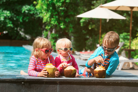 快乐的孩子喝椰子鸡尾酒上海滩度假村