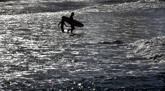 冲浪者背着她在海滩上的冲浪板