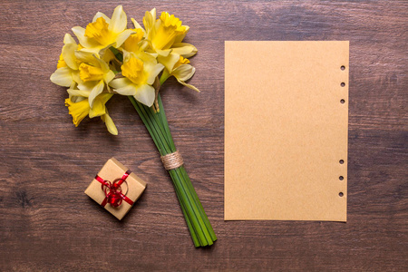工作场所用一条红丝带，纸和黄水仙花摆在一个木制的背景一件礼物