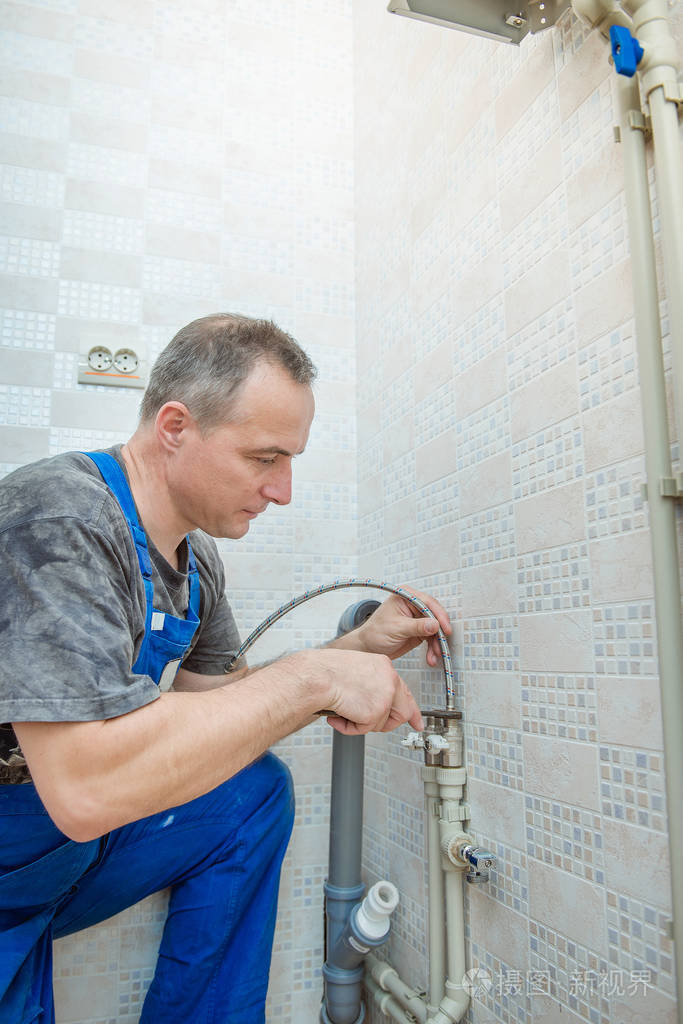 帅气的水管工人更换厨房水龙头