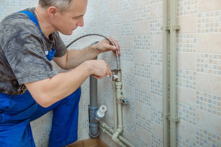 工人安装水管帅气的水管工人更换厨房水龙头照片