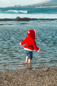 可爱的男婴，在海水中的红色圣诞老人外套