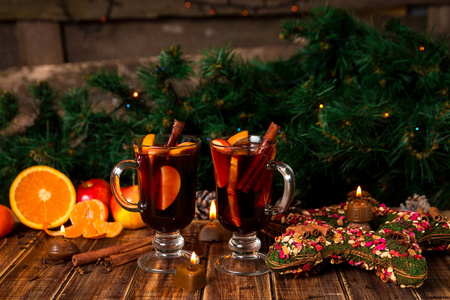 木制的桌子上香料和水果的甜酒。圣诞装饰品在背景中。两个眼镜。冬季气候变暖与周围的配方成分的饮料