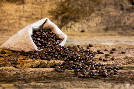 咖啡豆和老木背景上的包。新鲜的咖啡豆和袋旧木头上