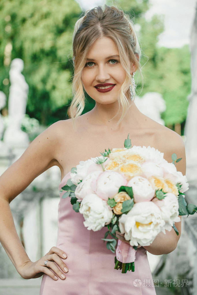 年轻漂亮的现代新娘时尚化妆与发型她手里拿着牡丹花束的肖像