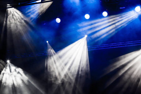白色和蓝色光线从透过烟雾在剧院或音乐会大厅聚光灯。照明设备演出或表演
