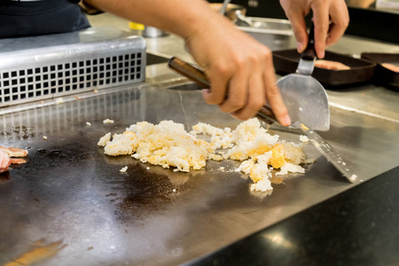 手的厨师烹饪大蒜炒米饭热平底锅在铜上