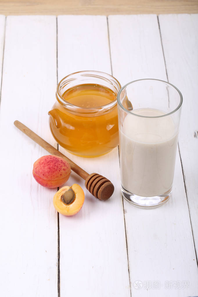 蜂蜜和一杯牛奶木制的桌子上