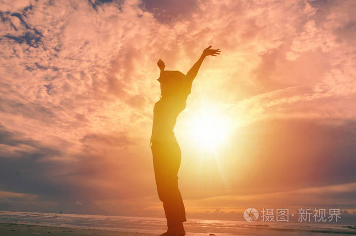 幸福的女人手抬高和美丽的日出在背景中