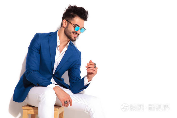 侧面图的笑优雅的年轻男子坐在椅子上