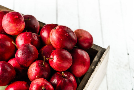 红苹果木包装箱，白色背景上的新鲜苹果堆在桌子上