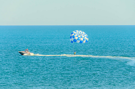 蓝色 parasail 翼拉扯了一艘船在海中，由水上滑翔伞