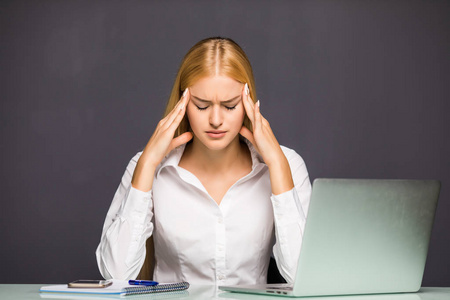 累了年轻人与头痛商业女性在办公室用笔记本电脑的肖像