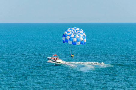 蓝色 parasail 翼拉扯了一艘船在海中，由水上滑翔伞