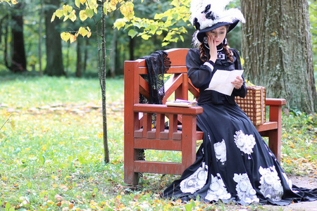 复古穿裙子的女孩过去世纪读信坐在板凳上