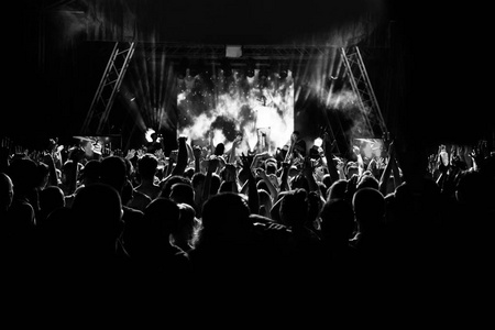 轮廓的人在一场音乐会，在明亮的光线中的场景。黑色和白色