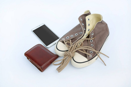 双新棕色运动鞋与智能手机和白色背景上的钱包