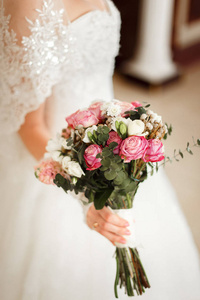新娘紧握着一束美丽的玫瑰和白色的花朵
