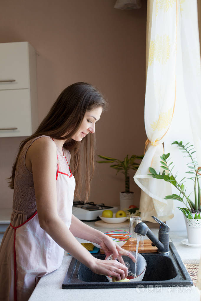 女孩的家庭主妇洗脏盘子在厨房里