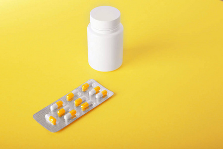 Prescripted 药品宽敞明亮黄色背景上一个小包。药 止痛药 药物 维生素，胶囊和白色药瓶附近包片