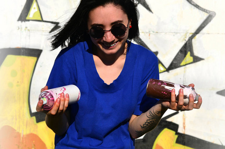 照片的一个女孩与气溶胶油漆罐在手上涂鸦墙背景