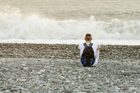 背包的年轻男人正坐在大洋彼岸。查看从背面
