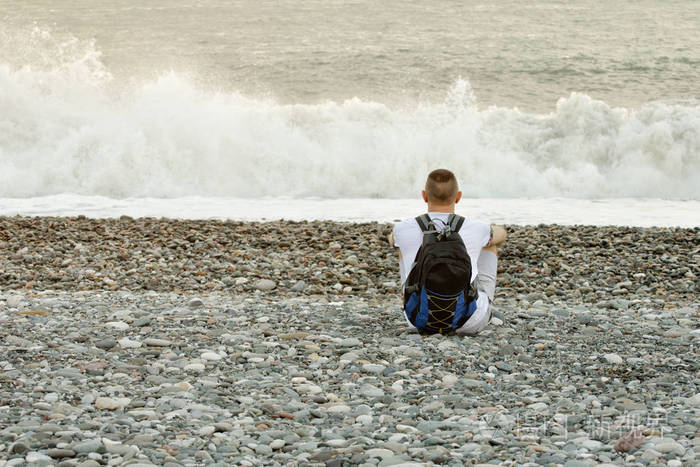 背包的年轻男人正坐在大洋彼岸查看从背面