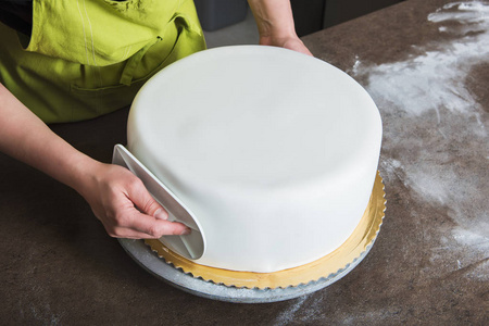 无法辨认装饰与白色翻糖婚礼蛋糕的面包店里的女人
