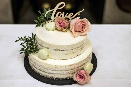 漂亮的婚礼蛋糕，奶油上带有文本爱顶粉红色的花朵玫瑰