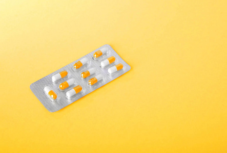 抗生素 维生素 止痛药药物或阿司匹林的特写包装。灰色和闪亮亮的黄色背景上的白色和黄色胶囊水泡