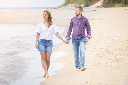 年轻夫妇沿着海走上海滩举行的爱情
